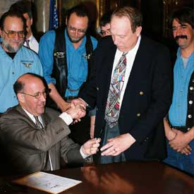 Govenor JIM DOYLE congratulates Attorney Michael F. Hupy and hands him a pen used to sign Wisconsin’s new helmet bill